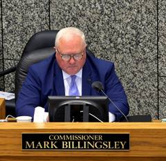 Shelby County Commissioner Mark Billingsley seated at the dais behind his nameplate, with a monitor and microphone.