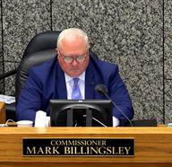 Shelby County Commissioner Mark Billingsley seated at the dais behind his nameplate, with a monitor and microphone.