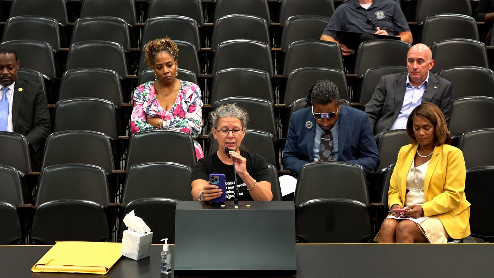 Public comment during a Shelby County Commission meeting, with a speaker at the microphone and attendees seated behind her.