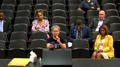 Public comment during a Shelby County Commission meeting, with a speaker at the microphone and attendees seated behind her.