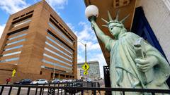 A weathered Liberty statue in the foreground, with the brick Shelby County Criminal Justice Center at 201 Poplar across the street in daylight.
