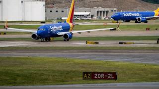 Passenger jets taxiing on airport apron and runway pavement past terminal buildings, representing the airport authorities restructured by state legislation.