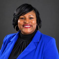 Portrait of Katrina Amos-Atkins, Collierville deputy town administrator, wearing a cobalt blue blazer against a gray background.