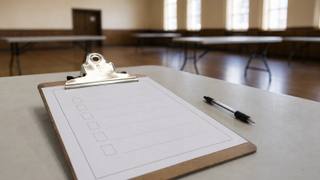 A blank ballot line on a clipboard resting on a table in a community hall with a pen beside it, representing the write-in line District 93 voters must use.