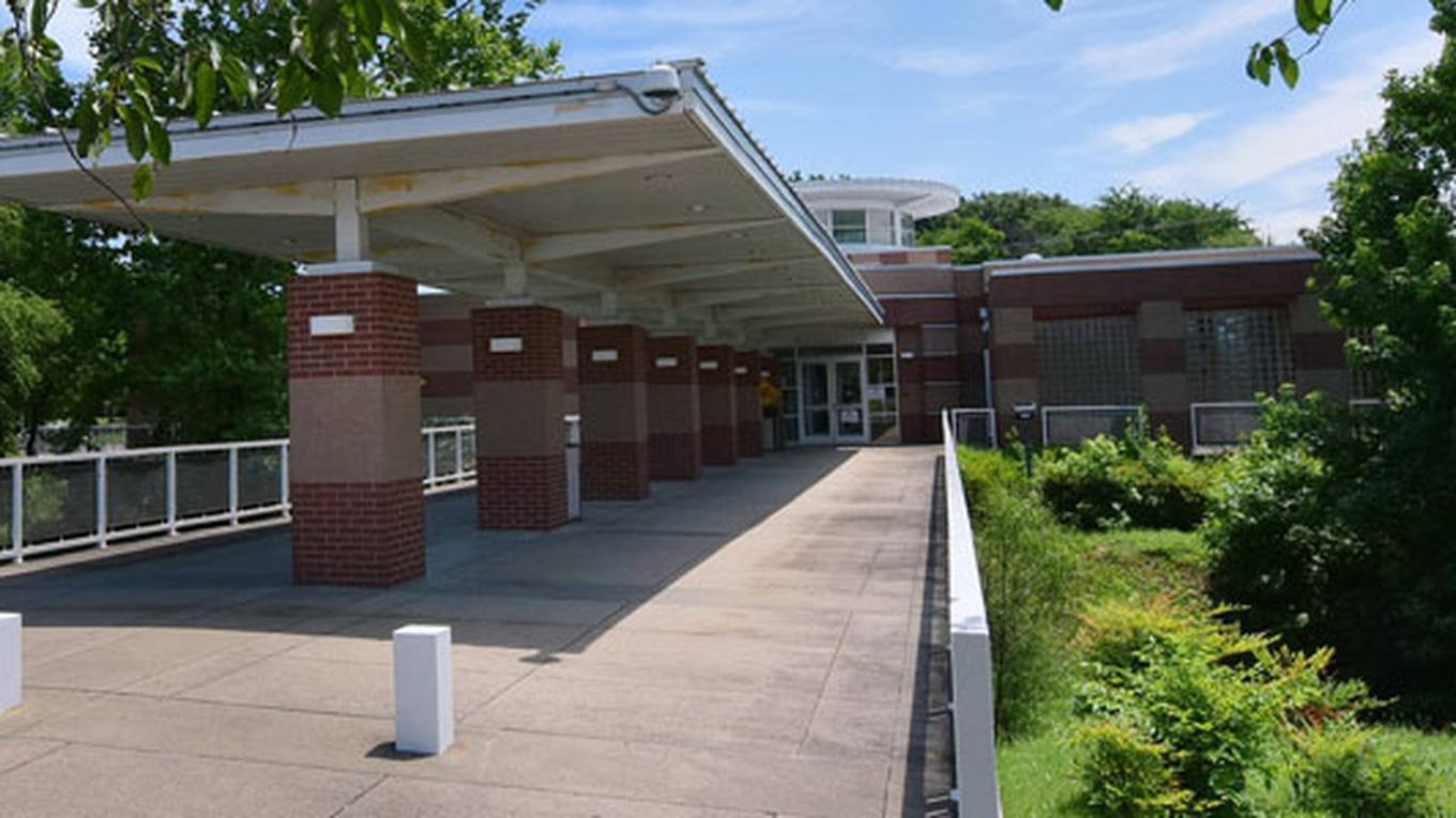 The covered entrance walkway of a suburban public library branch on a sunny day.