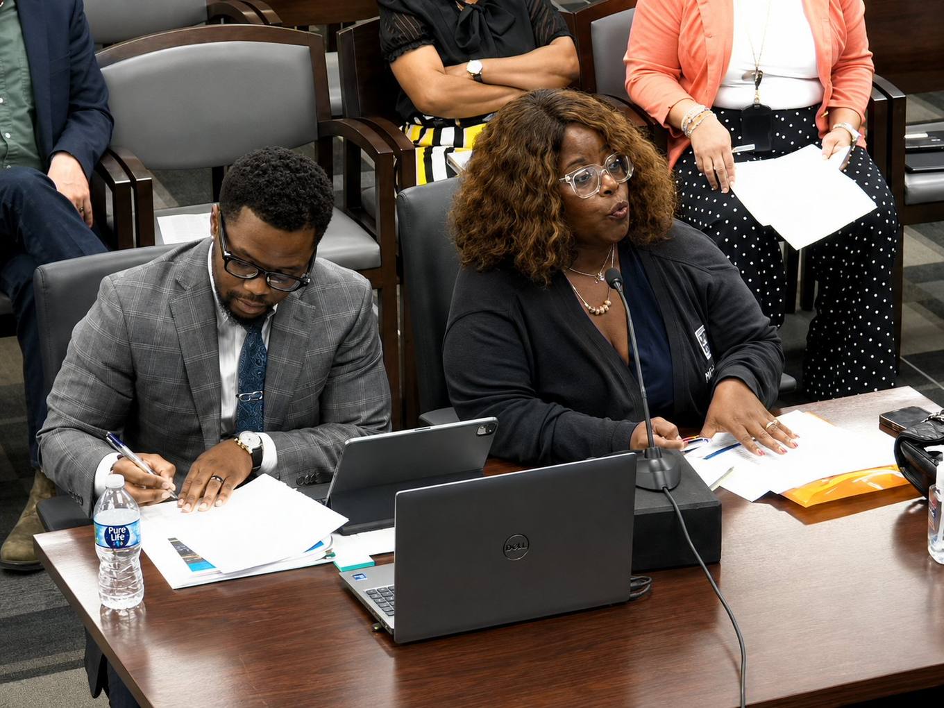Two Housing and Community Development staff members seated at a witness table with laptops and papers speak into a microphone during a Memphis City Council committee meeting.
