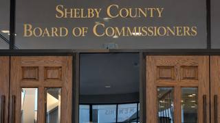 Gold lettering reading Shelby County Board of Commissioners above the wooden doors of the commission chamber.