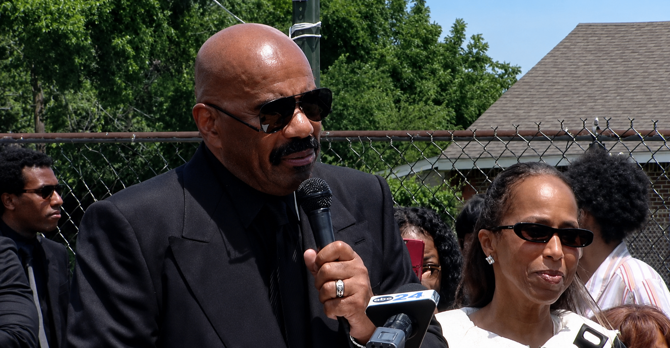 Steve Harvey speaks into an ABC24 microphone alongside Marjorie Harvey at a Memphis street naming ceremony