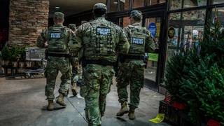 Members of the Tennessee National Guard walk a Memphis storefront sidewalk on patrol.