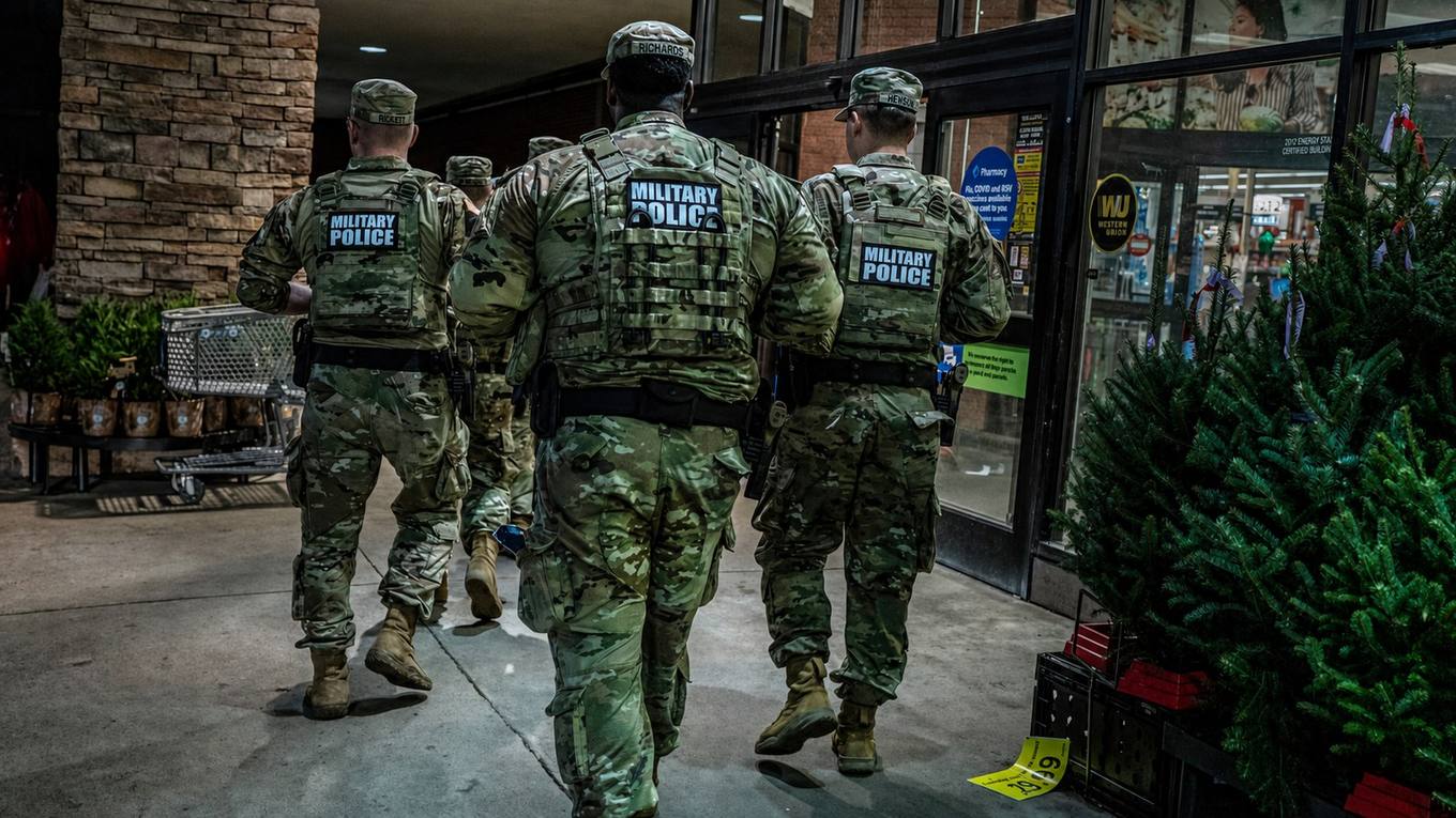 Members of the Tennessee National Guard walk a Memphis storefront sidewalk on patrol.