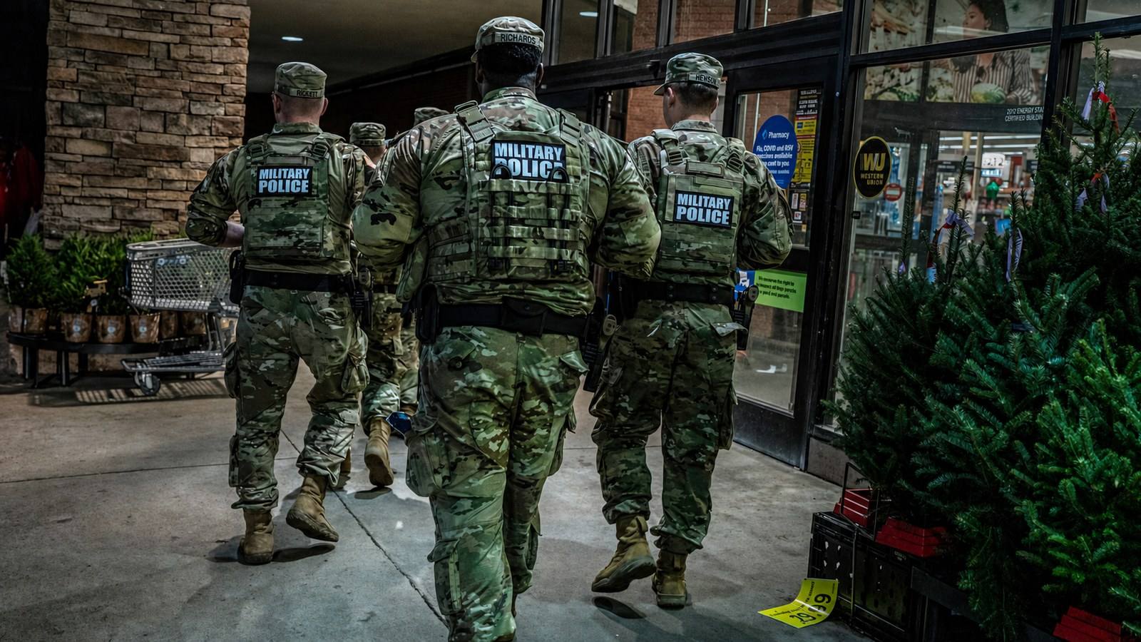 Members of the Tennessee National Guard walk a Memphis storefront sidewalk on patrol.