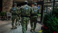Members of the Tennessee National Guard walk a Memphis storefront sidewalk on patrol.