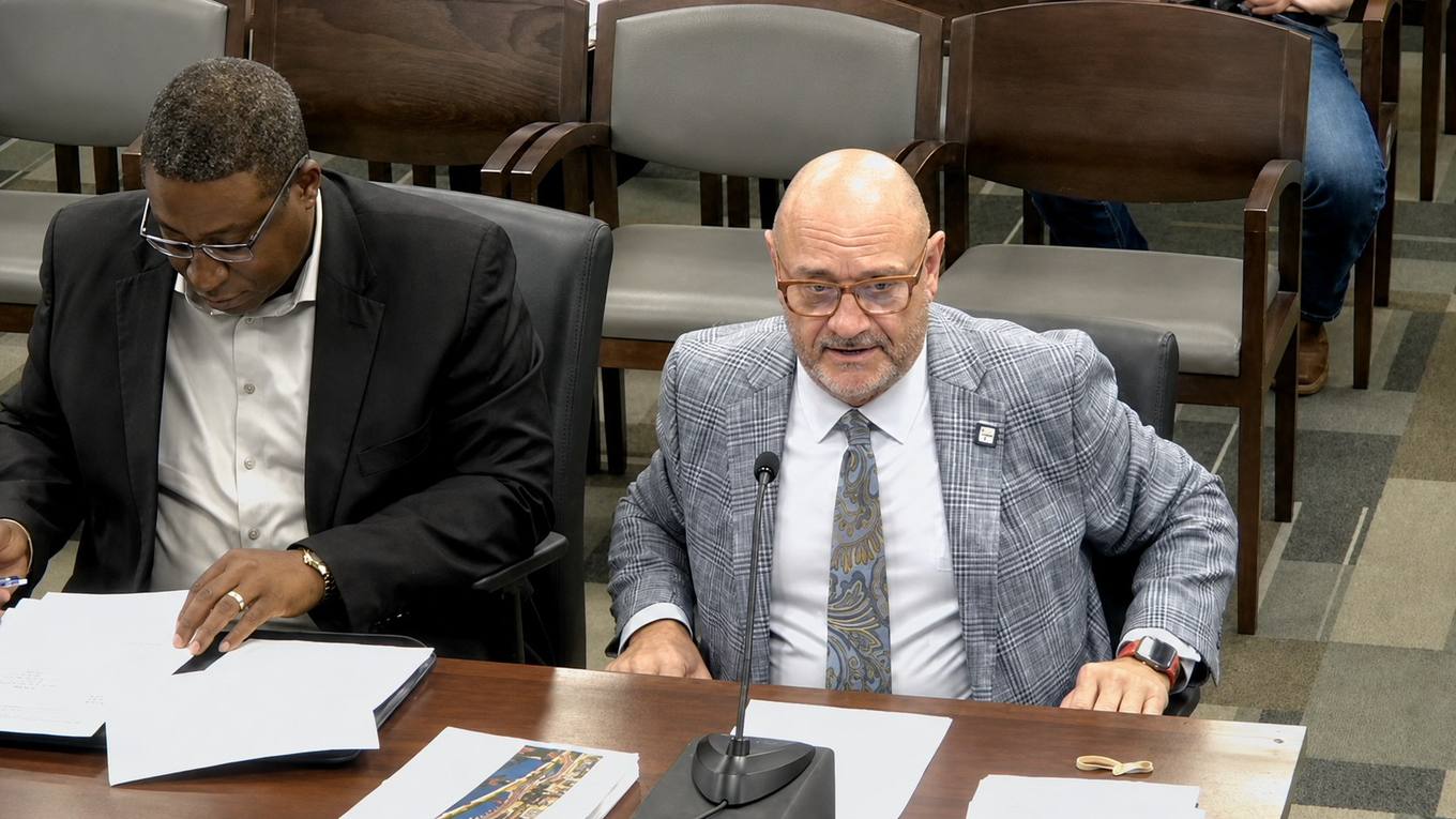 Two City of Memphis finance officials seated at a witness table during a council committee meeting, one speaking into a microphone.