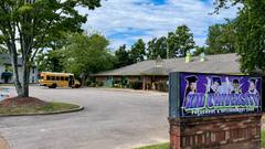 The Kid University childcare center sign and building in Cordova, seen from the parking lot with a small school bus parked outside.