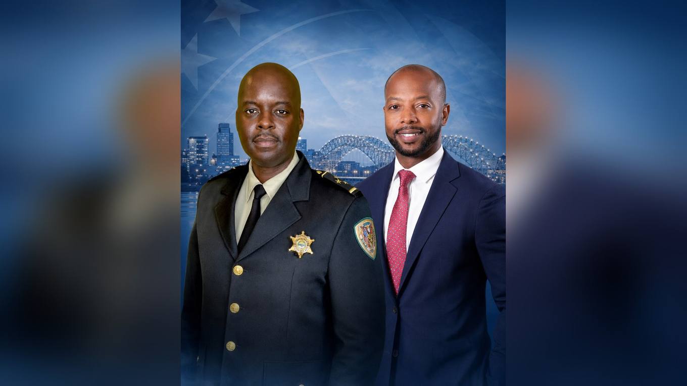 Shelby County Chief Deputy Anthony J. Buckner in uniform and Commissioner Mickell M. Lowery in a suit, photographed against a Memphis skyline and Hernando de Soto Bridge backdrop.