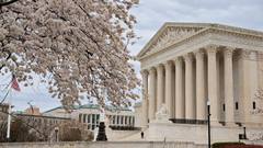 The U.S. Supreme Court building in Washington, D.C., seen past blossoming cherry trees.