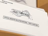 Close-up of an official election mail envelope marked Official Absentee Balloting Material - First-Class Mail.