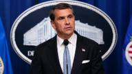 Todd Blanche speaking at a podium in front of the U.S. Department of Justice seal.