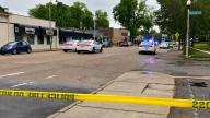 Memphis police cars and yellow police tape blocking a Cooper-Young street near storefronts after a shooting.