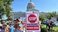 Protesters hold People Not Politicians signs outside the Missouri State Capitol in Jefferson City