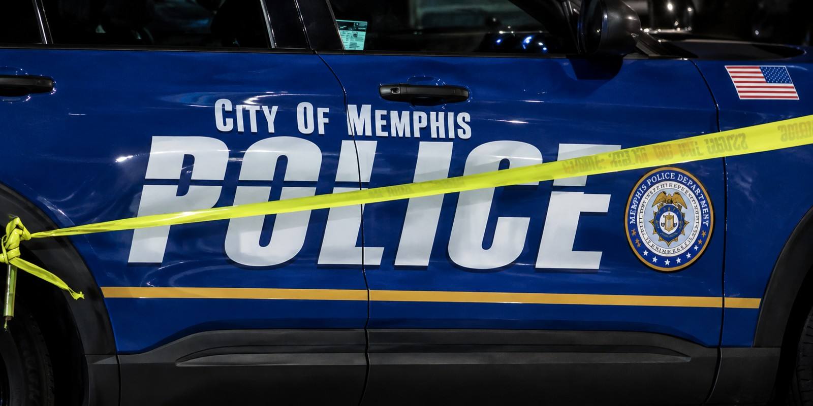 A blue Memphis Police Department patrol car behind yellow crime-scene tape.
