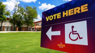 An empty early-voting polling place with folding tables and voting booths in daylight.
