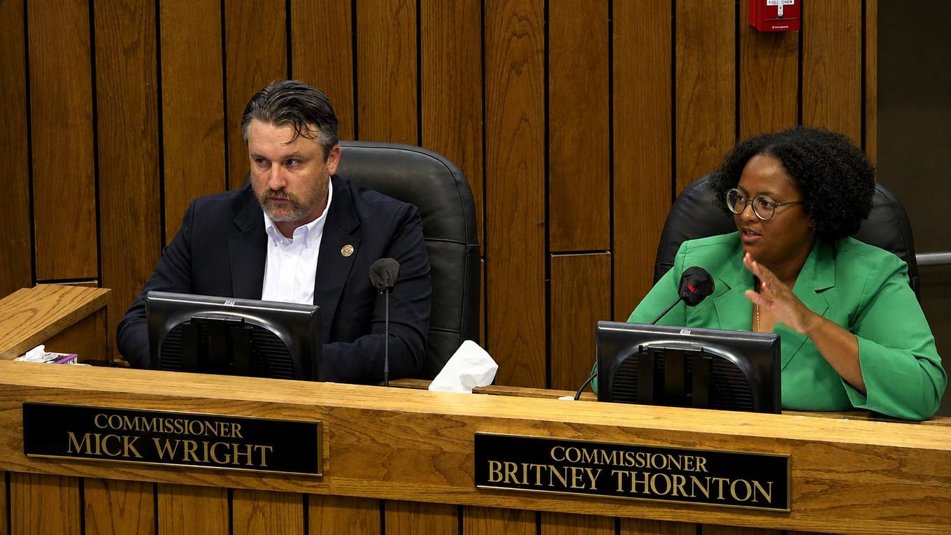 Two Shelby County commissioners seated at the dais during a commission meeting, one speaking into a microphone.