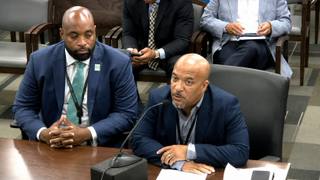 Two city officials seated at a committee table, one speaking into a microphone, during a Memphis City Council committee meeting.