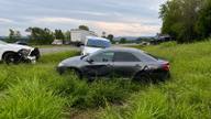 Two damaged cars in the grass beside a Tennessee highway with a patrol vehicle and ambulance responding