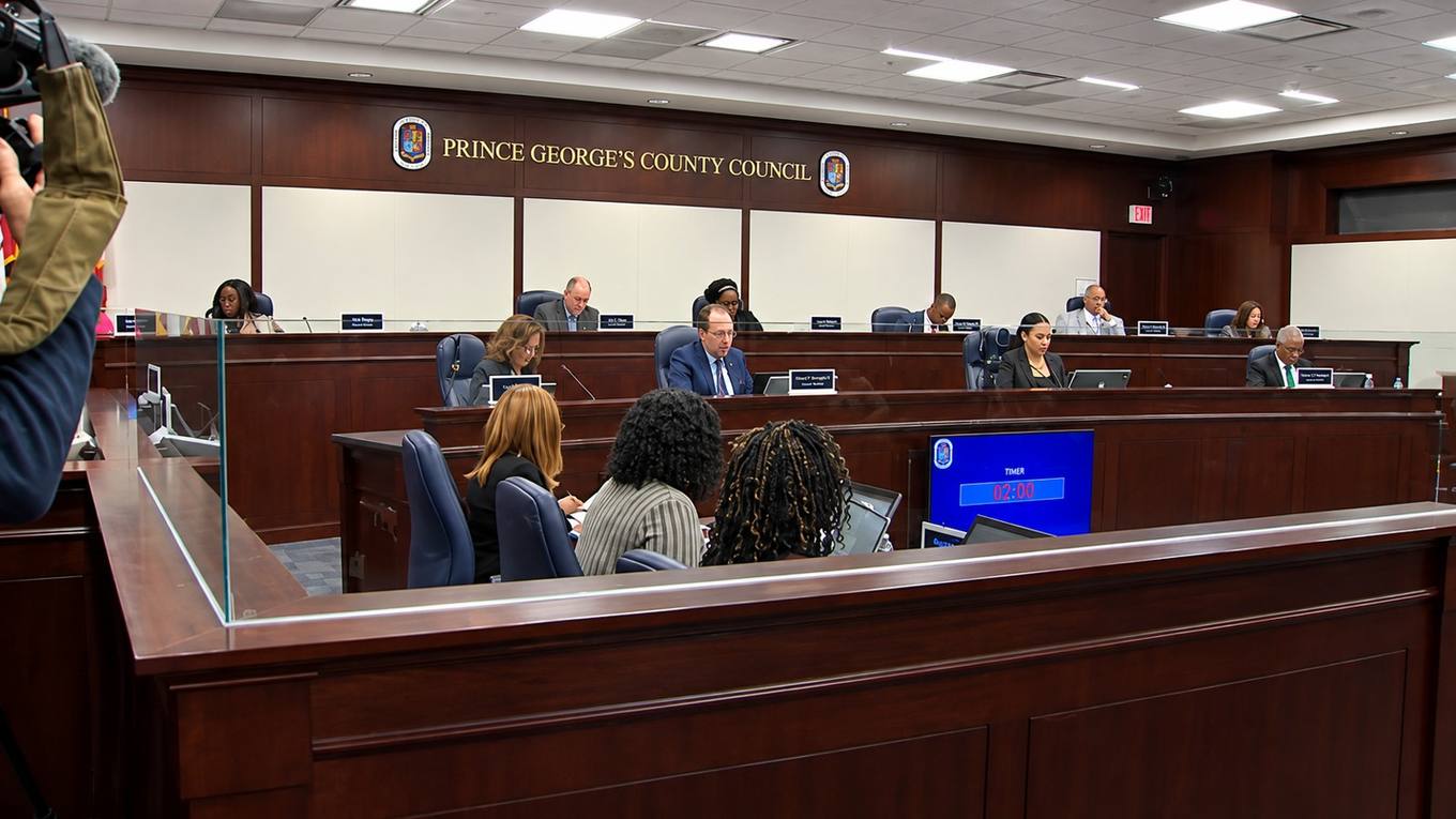 Prince George's County Council members seated at the dais inside the council chamber, with staff seated in the foreground.