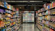 A nearly empty grocery cart in a quiet supermarket aisle under fluorescent light.