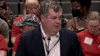 A city official speaks into a microphone at a Memphis City Council meeting with audience members seated behind him.