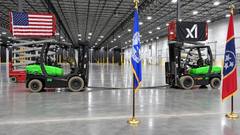 Forklifts and American, Memphis and Tennessee flags inside a large industrial hall, with xAI banners displayed on equipment.