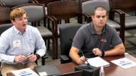 Two TDOT presenters seated at a committee table with a microphone, notebook and documents during a Memphis City Council committee meeting.