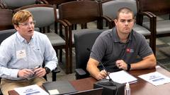 Two TDOT presenters seated at a committee table with a microphone, notebook and documents during a Memphis City Council committee meeting.
