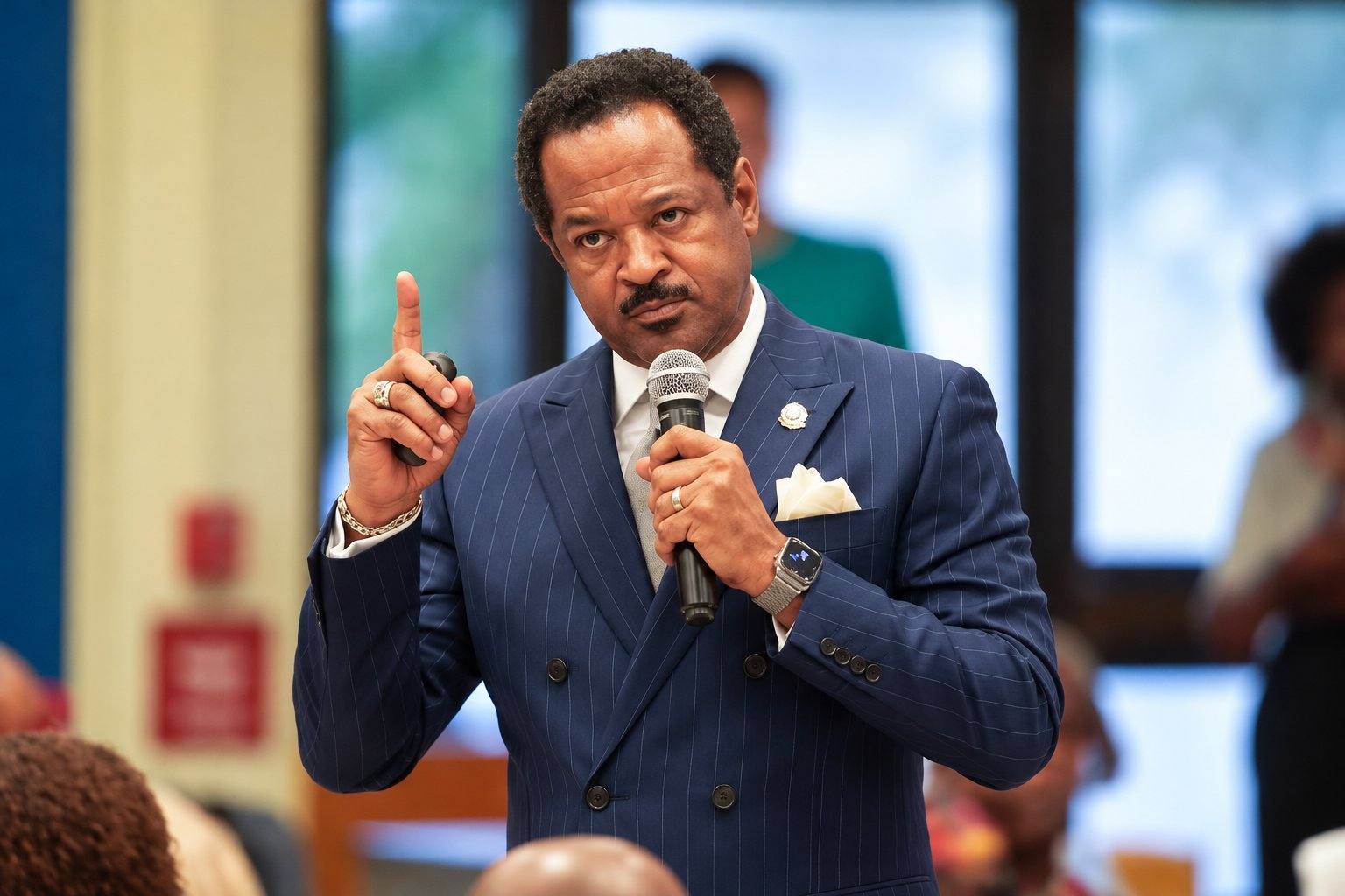 Memphis-Shelby County Schools Superintendent Roderick Richmond, wearing a blue pinstripe suit, speaks into a handheld microphone with one finger raised.