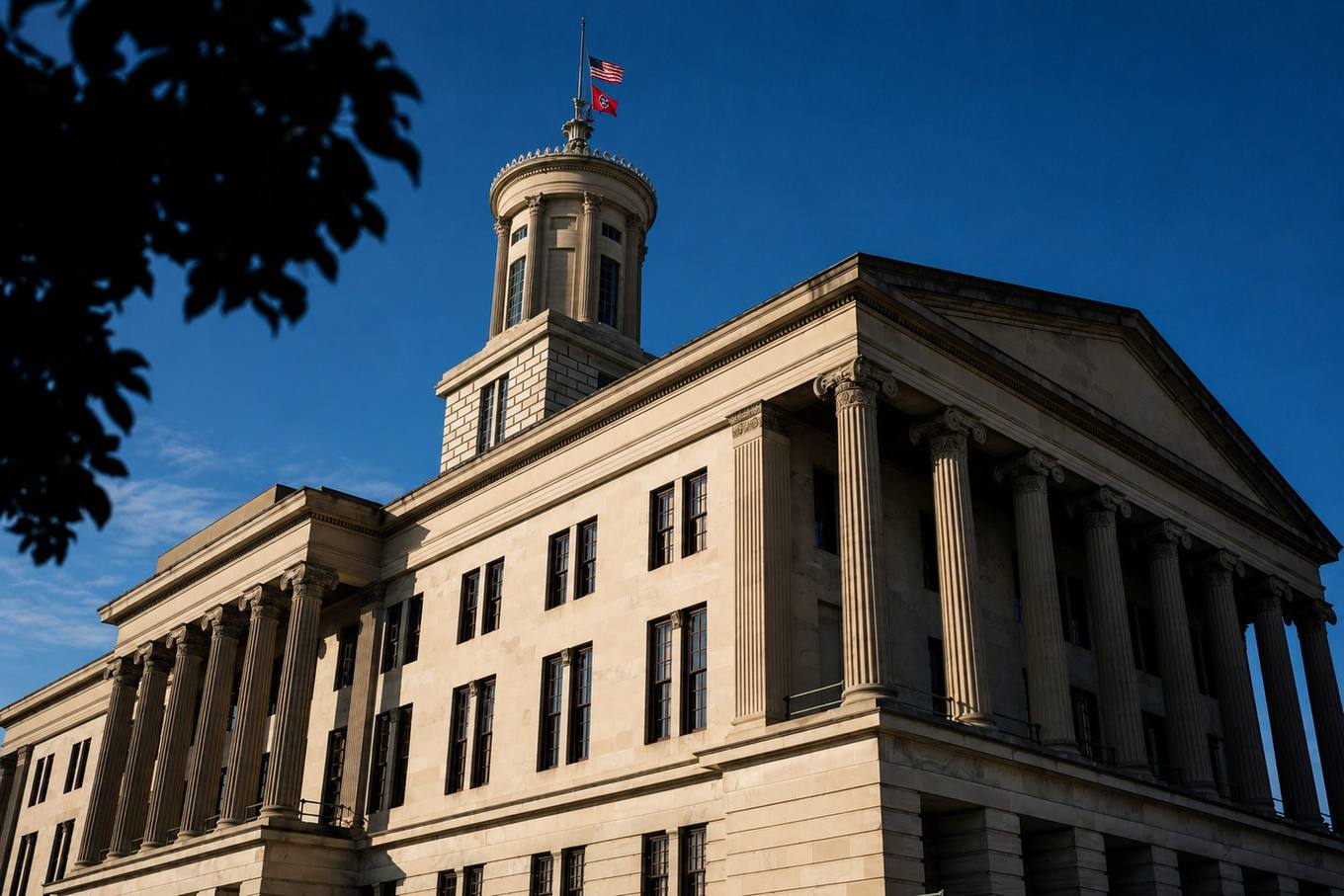 A limestone state capitol building with tall columns at golden hour, long shadows across the plaza.