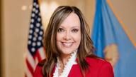 Oklahoma State Auditor and Inspector Cindy Byrd standing before United States and Oklahoma flags.